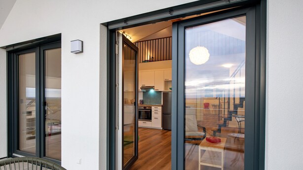 A modern interior with a kitchen, dining area, and a staircase leading to an upper level.