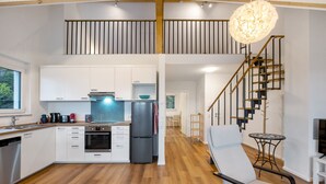 A modern kitchen with white cabinets, a stainless steel oven, and a black refrigerator.