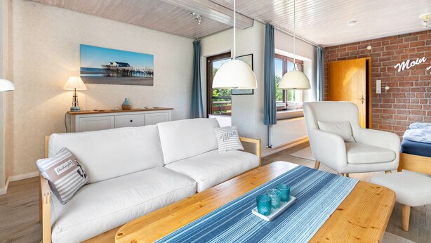 A modern living room with a sofa, a wooden coffee table, a chair, and a dining table. There is a painting on the wall, a lamp, and a door with a sign. - Apartment 'Gode Tied' with Private Terrace, Balcony and Wi-Fi (Wesseln)