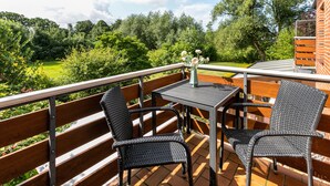 A balcony with a table and chairs, a vase with flowers, and a view of a green landscape. - Apartment 'Gode Tied' with Private Terrace, Balcony and Wi-Fi (Wesseln)