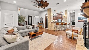 A modern living room with a grey sofa, wooden coffee table, and a stone accent wall. - The Cove: Heated Pool, Hot Tub, Lake Access (Shady Shores)