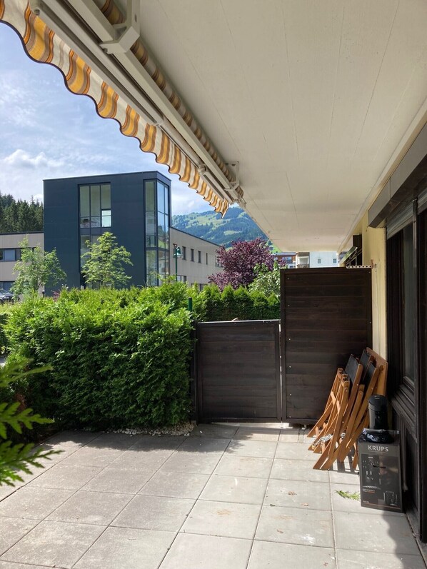 A covered patio area with a view of a modern building and mountains in the background.