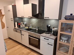A modern kitchen with a stove, sink, oven, and a cabinet with glass doors.