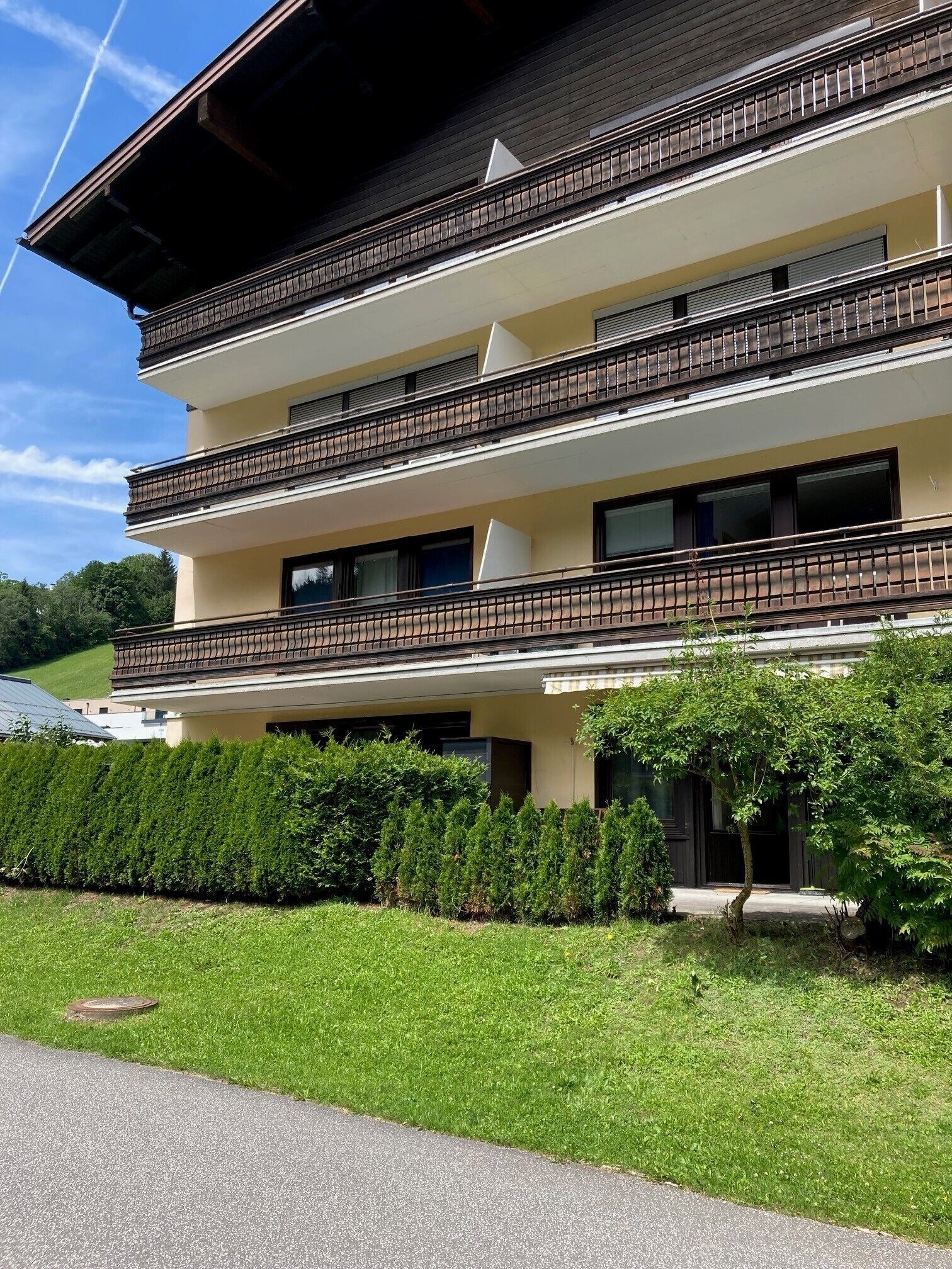 Un immeuble à plusieurs étages doté de balcons, d’un toit plat et d’une pelouse bien entretenue.