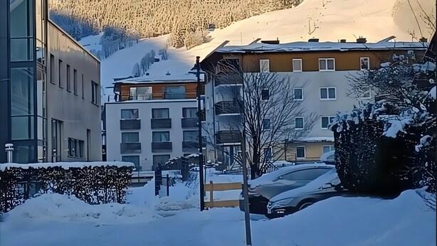 Une montagne enneigée, avec des bâtiments visibles au premier plan.