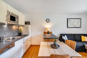 Une cuisine moderne équipée d’un four à micro-ondes, d’un évier et d’une table à manger en bois.