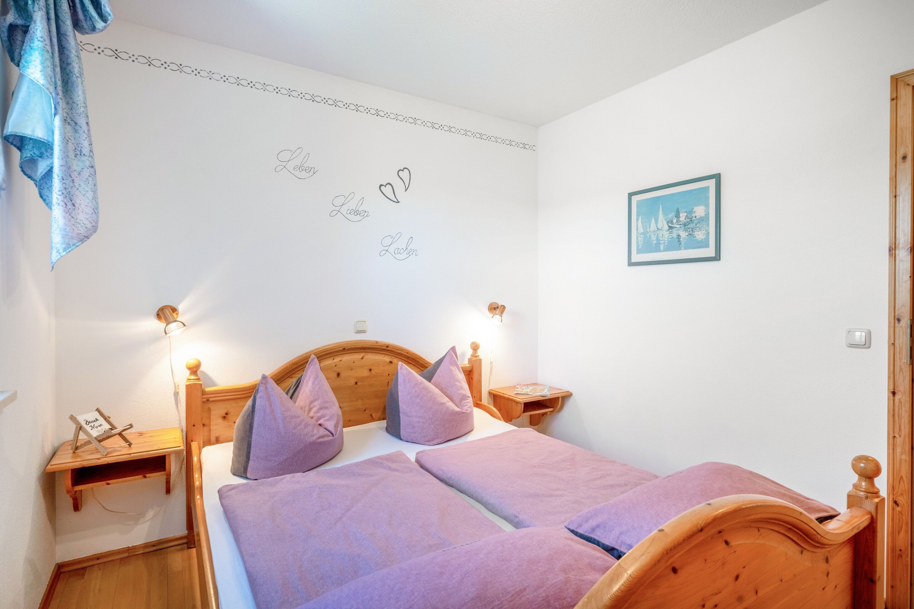 Ein Schlafzimmer mit einem hölzernen Bett, zwei Nachttischen, einer Wandleuchte und einem gerahmten Bild.