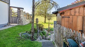 A rustic wooden gate, a stone wall, and a wooden fence in a garden setting.