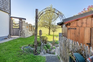 Une porte en bois rustique, un mur de pierres et une clôture en bois, le tout dans un cadre de jardin.