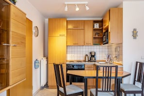 Una cocina compacta con armarios de madera, estufa, microondas y una mesa de comedor con sillas.