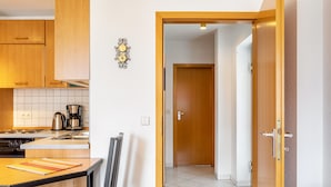A kitchen with wooden cabinets, a coffee maker, and a dining table with chairs. - Apartment 'Tannenblick 3-2' with Shared Garden, Balcony and Wi-Fi (Oberhof)