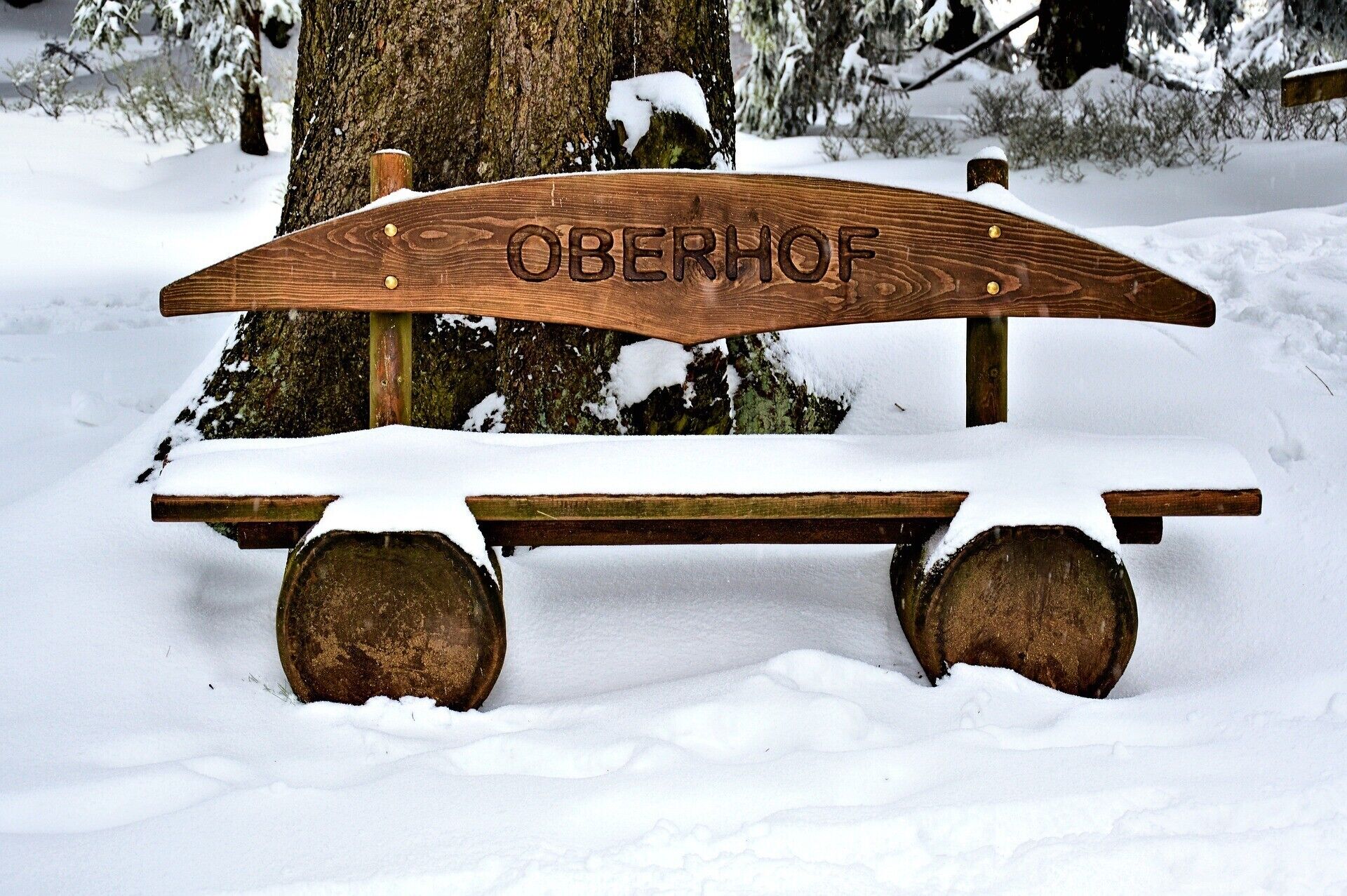 Een houten bank met de tekst 'Oberhof' in een besneeuwde omgeving.
