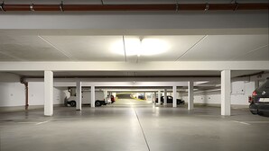 Un estacionamiento interior con pilares blancos, pisos de concreto y un pasillo central.