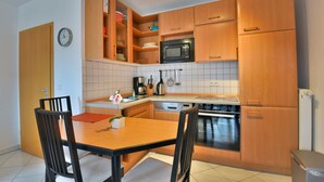 Una cocina moderna con armarios de madera, microondas, estufa y una mesa de comedor con sillas.
