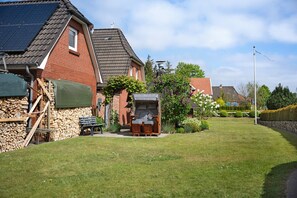 Un quartier résidentiel avec une maison en briques, des panneaux solaires, un petit jardin et un banc en bois.