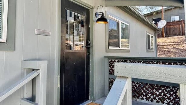 Un porche abrité avec une porte noire, une petite fenêtre et un luminaire fixé au mur.