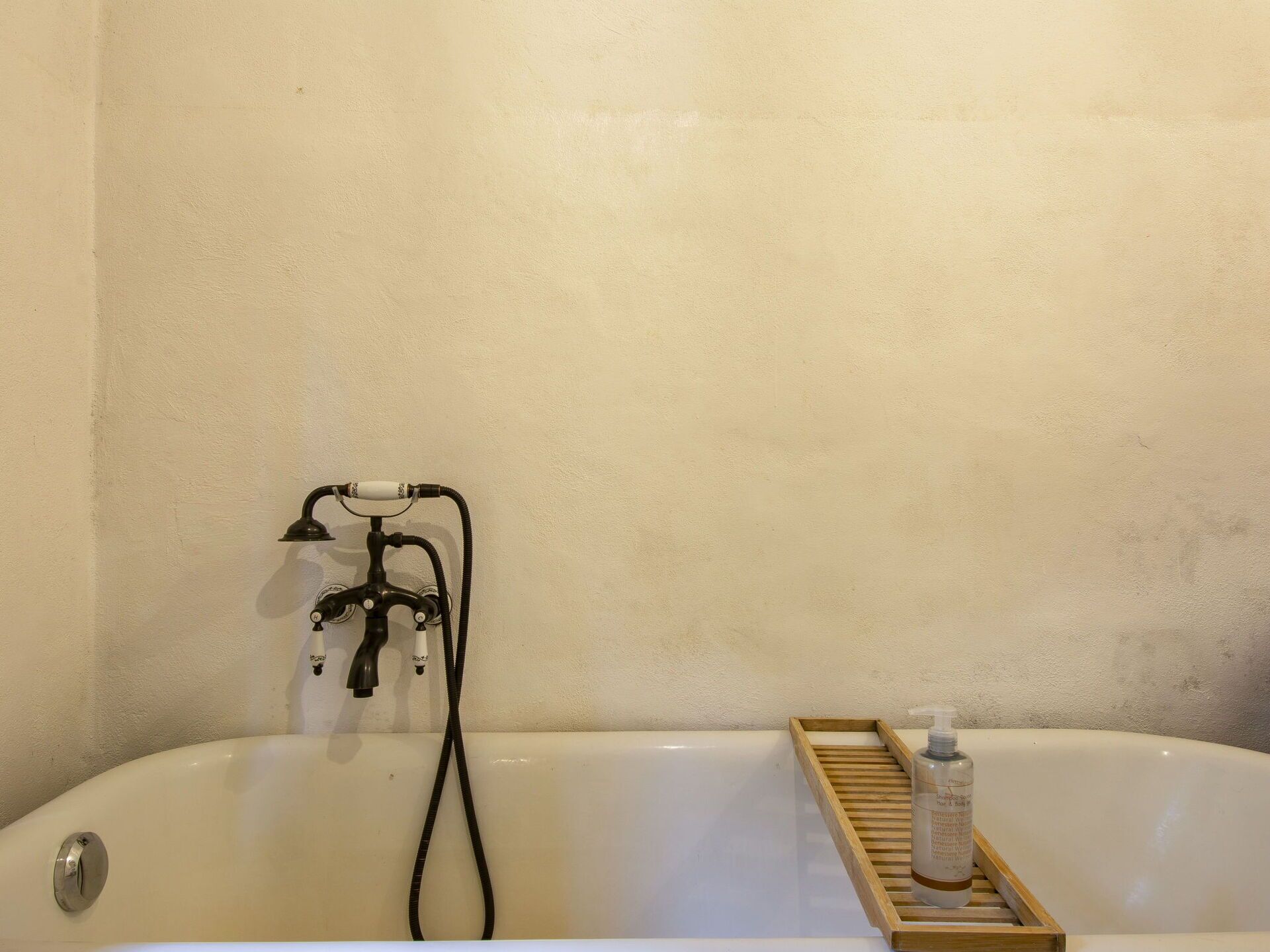 Une baignoire avec un plateau en bois et une bouteille de shampoing.