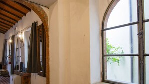 A corridor with a tiled floor, a wooden ceiling, and a window with a view of greenery outside. - Cosy apartment for 2 people with private pool, TV, patio and pets allowed (Barga)