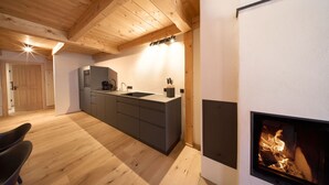 A modern kitchen with wooden beams, a built-in stove, and a dining area with a chair.
