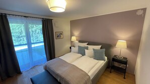 A hotel room with a large bed, two bedside tables with lamps, a view of greenery through the window, and a small picture on the wall. - Vacation home cloverleaf 175sqm with balcony and terrace (Siegsdorf)