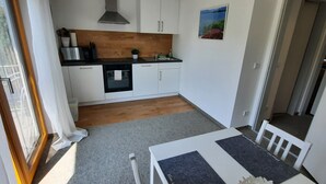 A compact kitchen with white cabinets, a black oven, and a wooden countertop.