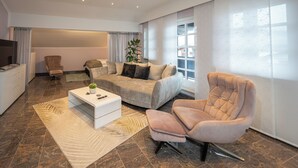 A modern living room with a sofa, armchair, coffee table, and a television.