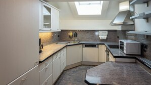 A modern kitchen with a skylight, granite countertops, and built-in appliances.