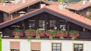 A row of chalet-style buildings with red-tiled roofs, arched windows, and flower boxes on the balconies.