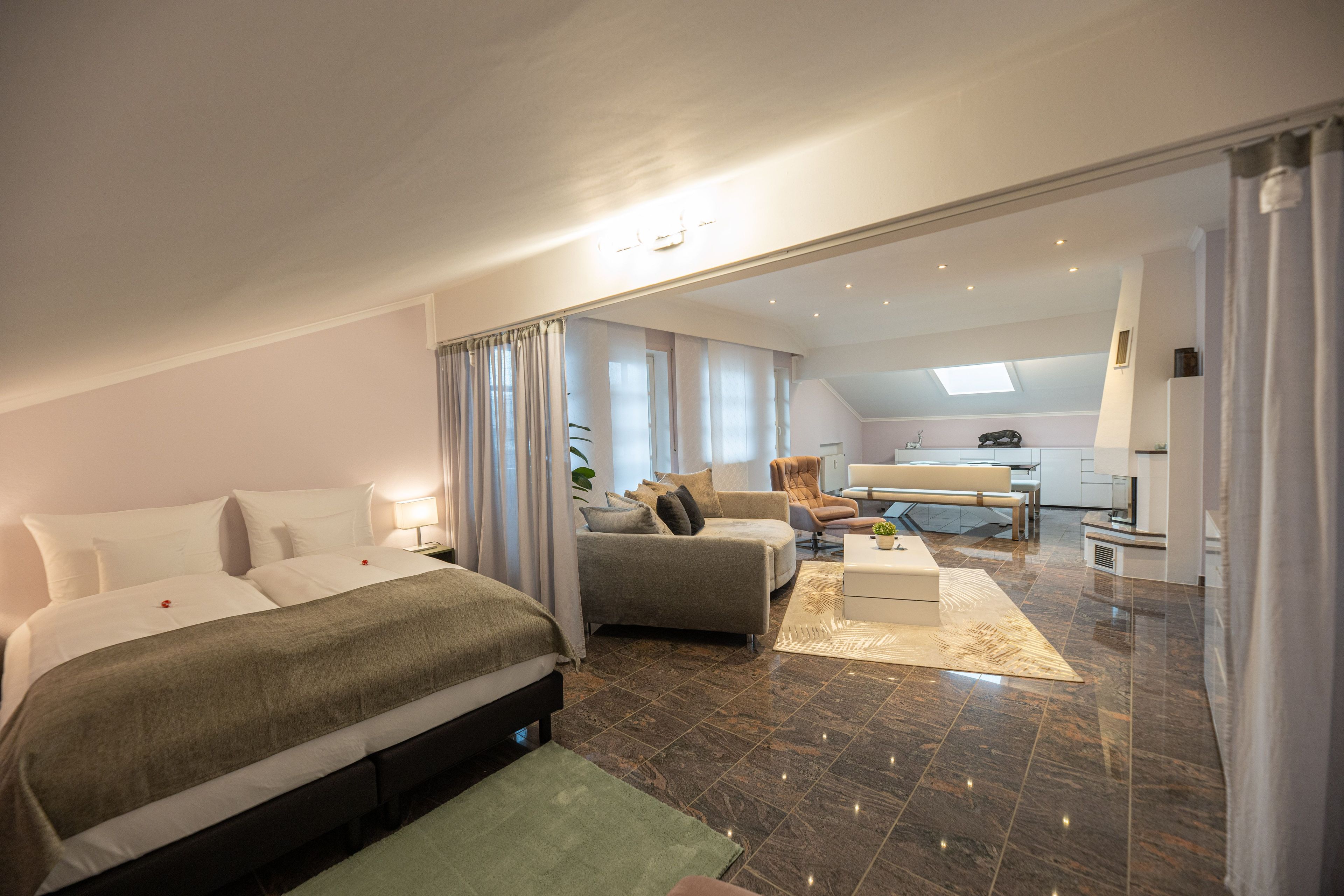 Una habitación de hotel moderna con una cama grande, un sofá, un comedor y una cocina.