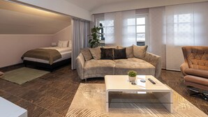 A modern living room with a sofa, a coffee table, a chair, a bed, and a large window.