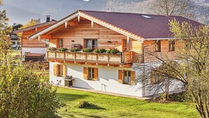 Un chalet en bois doté d’un balcon, entouré d’une végétation luxuriante et de montagnes.