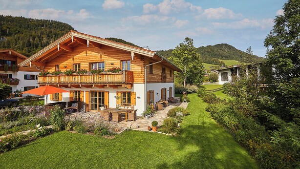 Un chalet en bois doté d’un balcon, d’une terrasse avec mobilier d’extérieur et d’un jardin bien entretenu.