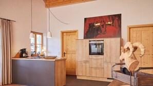 Une cuisine moderne avec des meubles en bois, un four encastré et un coin repas agrémenté d’une chaise au style rustique.