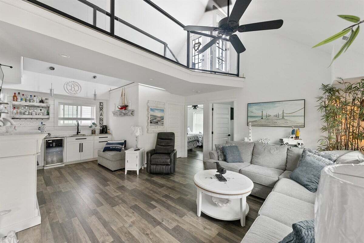 A spacious living area with a high ceiling, a ceiling fan, a dining table, and a sofa.