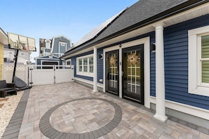 Una propiedad residencial con patio empedrado, aro de baloncesto y garaje.