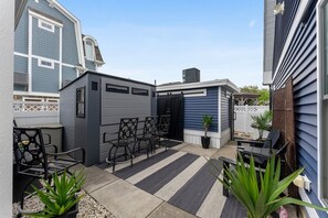 Un patio con una zona de estar, un cobertizo pequeño y una planta en maceta.