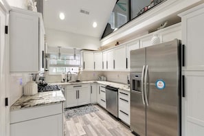 A modern kitchen with white cabinetry, stainless steel appliances, and a granite countertop.
