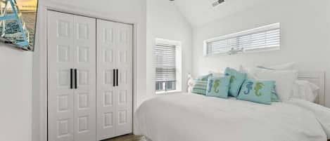 A bedroom with a bed, a ceiling fan, a wardrobe, and a window with blinds.