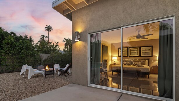 A modern hotel room with a sliding glass door, a ceiling fan, and a bed with patterned bedding. - Azul Oasis by AvantStay | Pool, Hot Tub, Firepit, Bocce Ball | Mins to Downtown (Palm Springs)