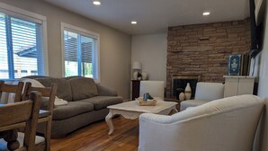 A living room with a stone fireplace, wooden flooring, and a sofa. - Beautiful home in Idaho Falls (Idaho Falls)