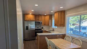 A modern kitchen with wooden cabinets, stainless steel appliances, and a dining area with a wooden table and chairs. - Beautiful home in Idaho Falls (Idaho Falls)
