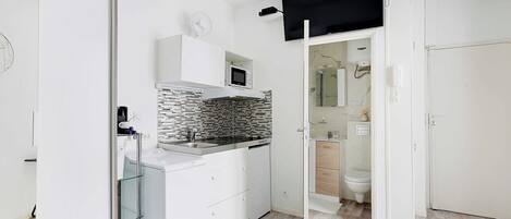 A compact kitchen with a microwave, stove, and modern sink.