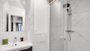 A modern bathroom with a marble sink, a glass shower enclosure, and a large mirror. - Peaceful Studio -2P- Moulin Rouge (Paris)