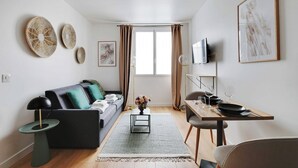 A modern living room with a sofa, a dining table set for two, and a TV mounted on the wall. - Peaceful Studio -2P- Moulin Rouge (Paris)