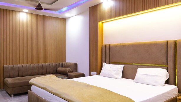 Una habitación de hotel moderna con una cama grande, un sofá y una mesita de noche.