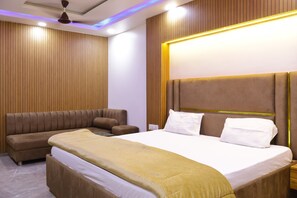 A modern hotel room with a large bed, a sofa, and a nightstand.