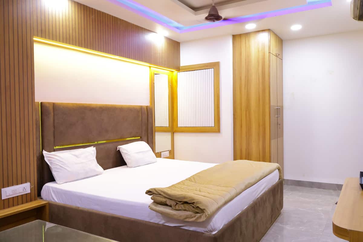 A modern hotel room with a bed, wooden paneling, a nightstand, and a mirror.
