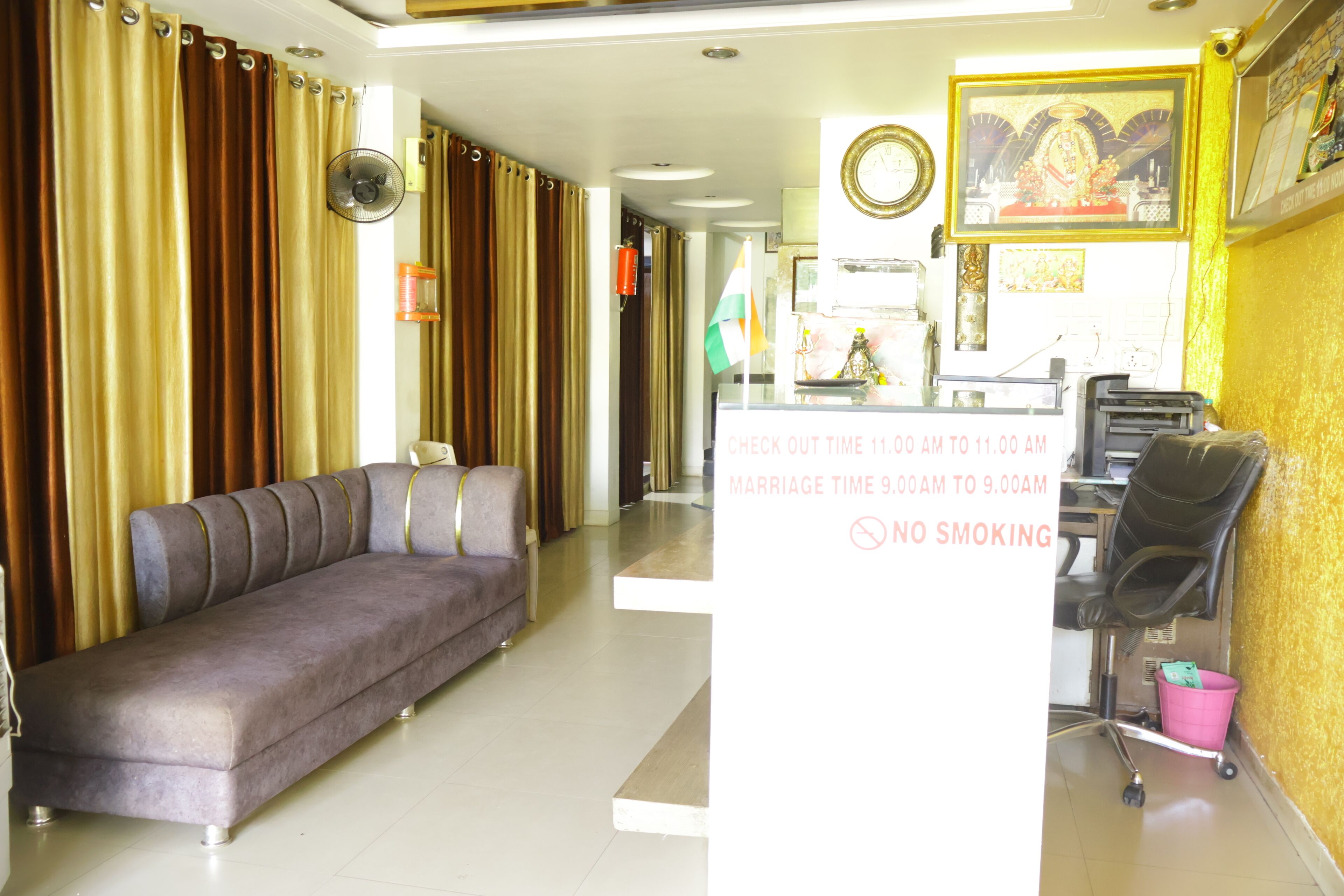 A hotel reception area with a sofa, a desk, and a no smoking sign.