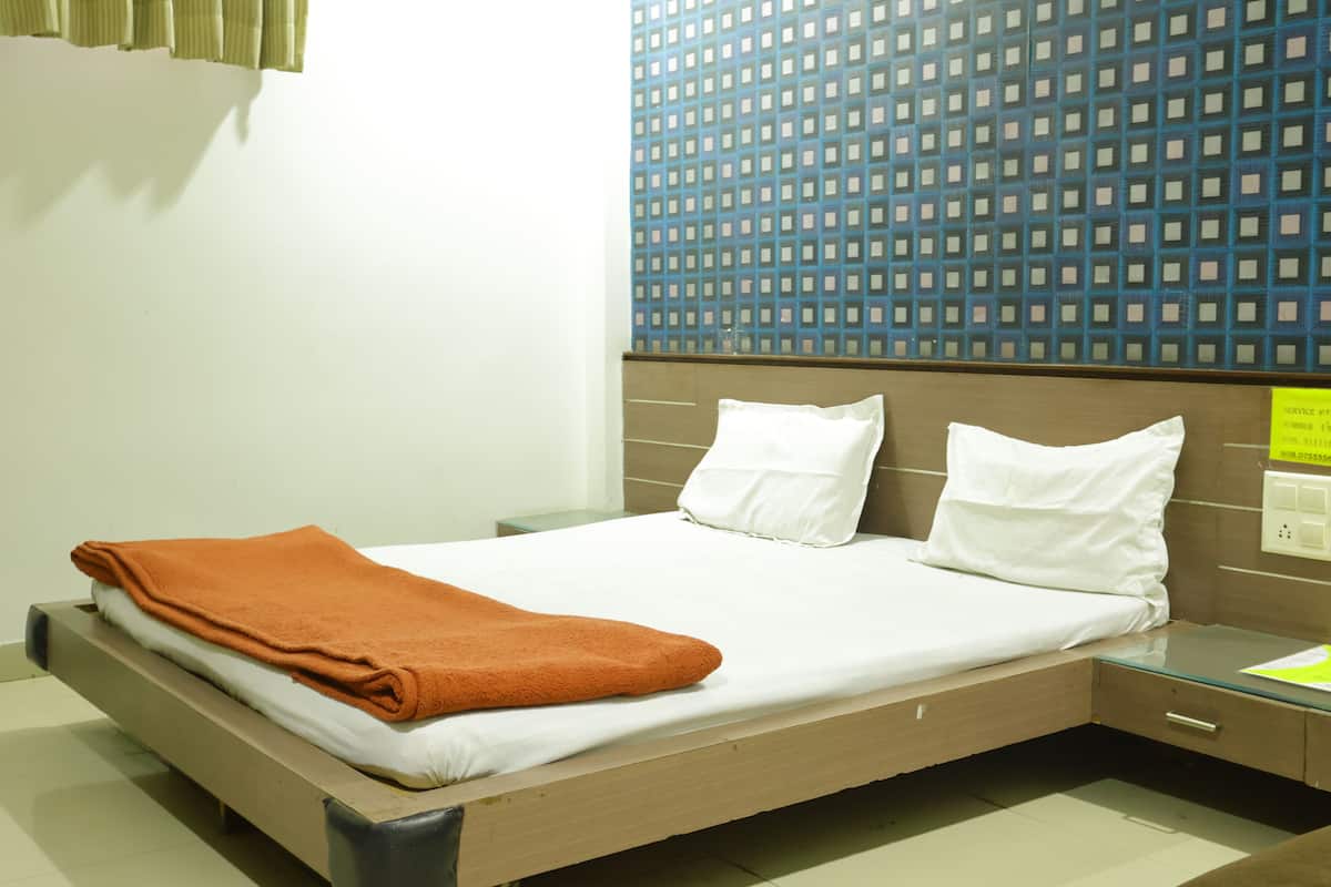 A hotel room with a bed, a nightstand, a drawer, and a wall with a geometric pattern.
