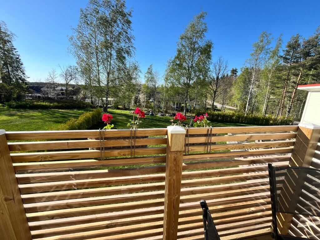 Une terrasse en bois offrant une vue sur une pelouse bien entretenue et des arbres.